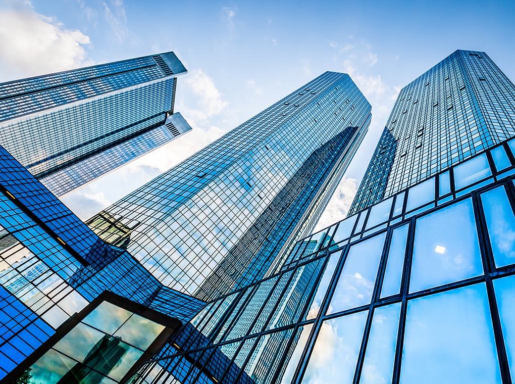 bottom,view,of,modern,skyscrapers,in,business,district,against,blue