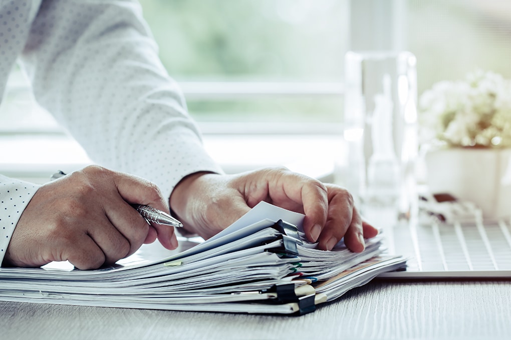 businessman,hands,holding,pen,for,working,in,stacks,of,paper