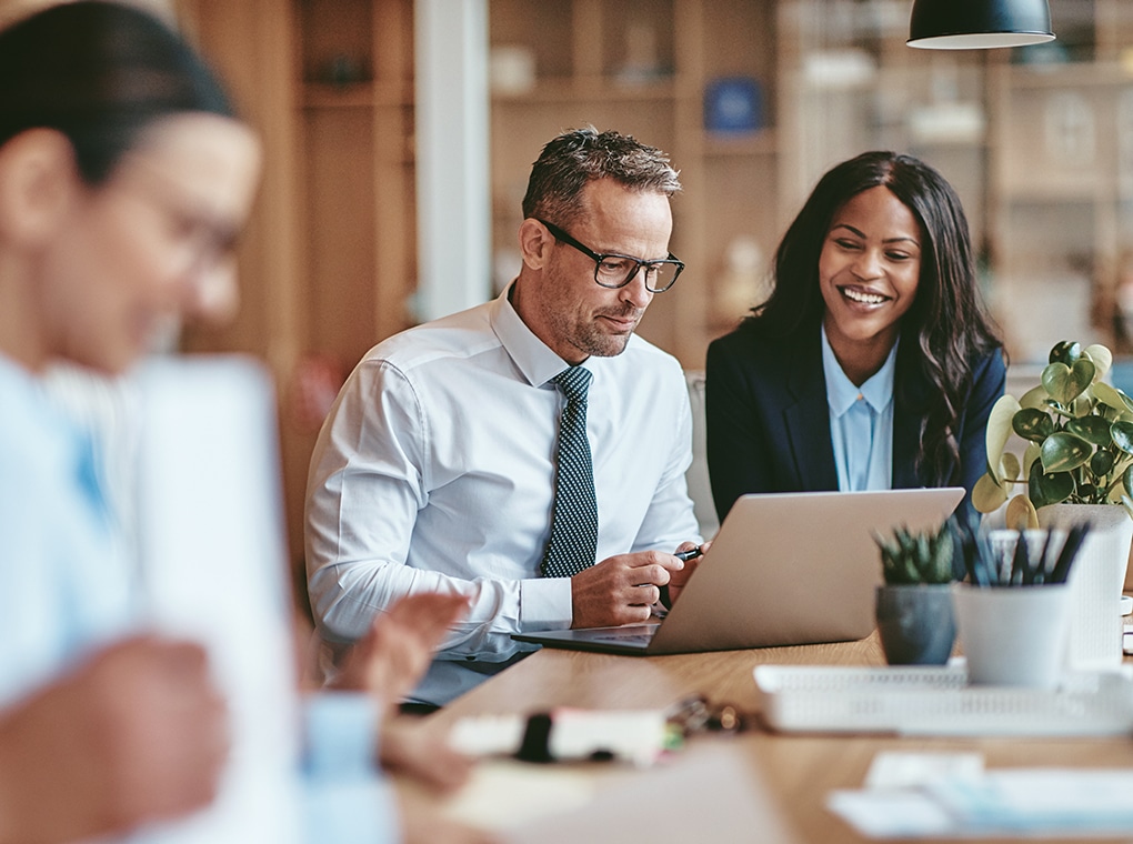 two,diverse,businesspeople,smiling,while,working,on,a,laptop,together