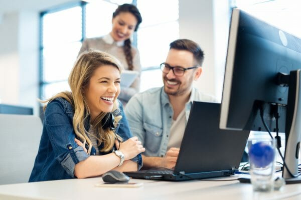 An image of business people and software developers working as a team and smiling in front of a computer