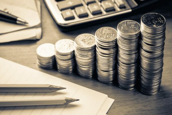 Heap coins stair with part of paper note, calculator and bills